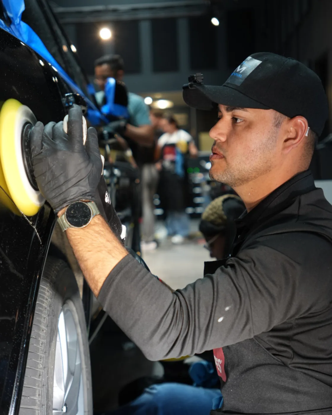 RM Auto Revival technician machine-polishing a black car during paint correction in Miami